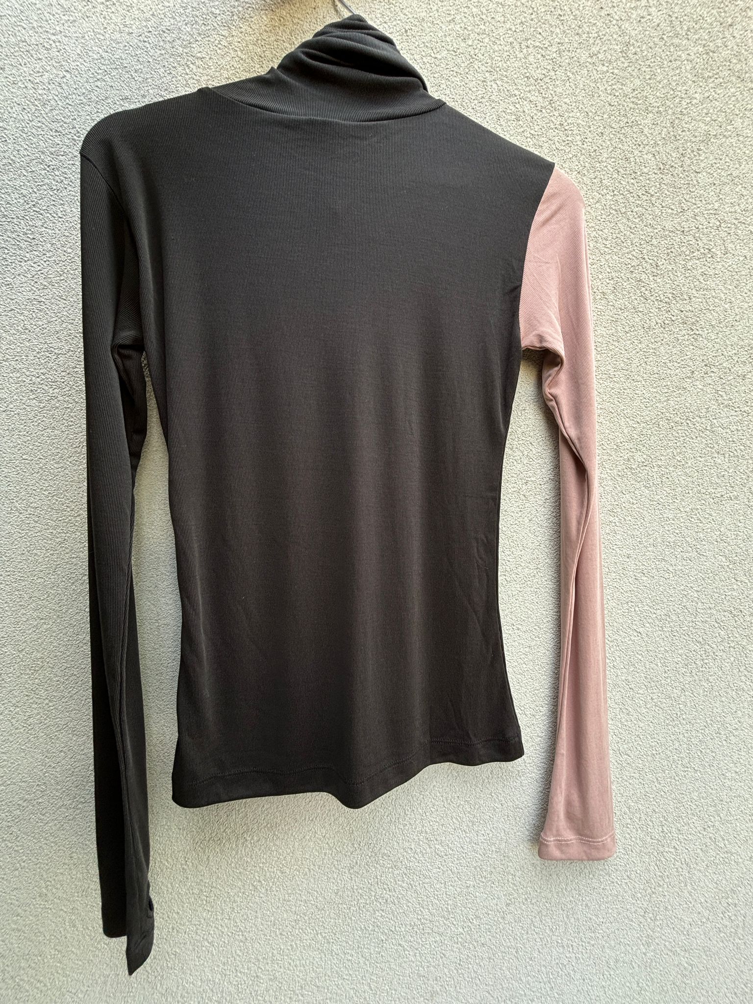 Black turtleneck with one pink sleeve